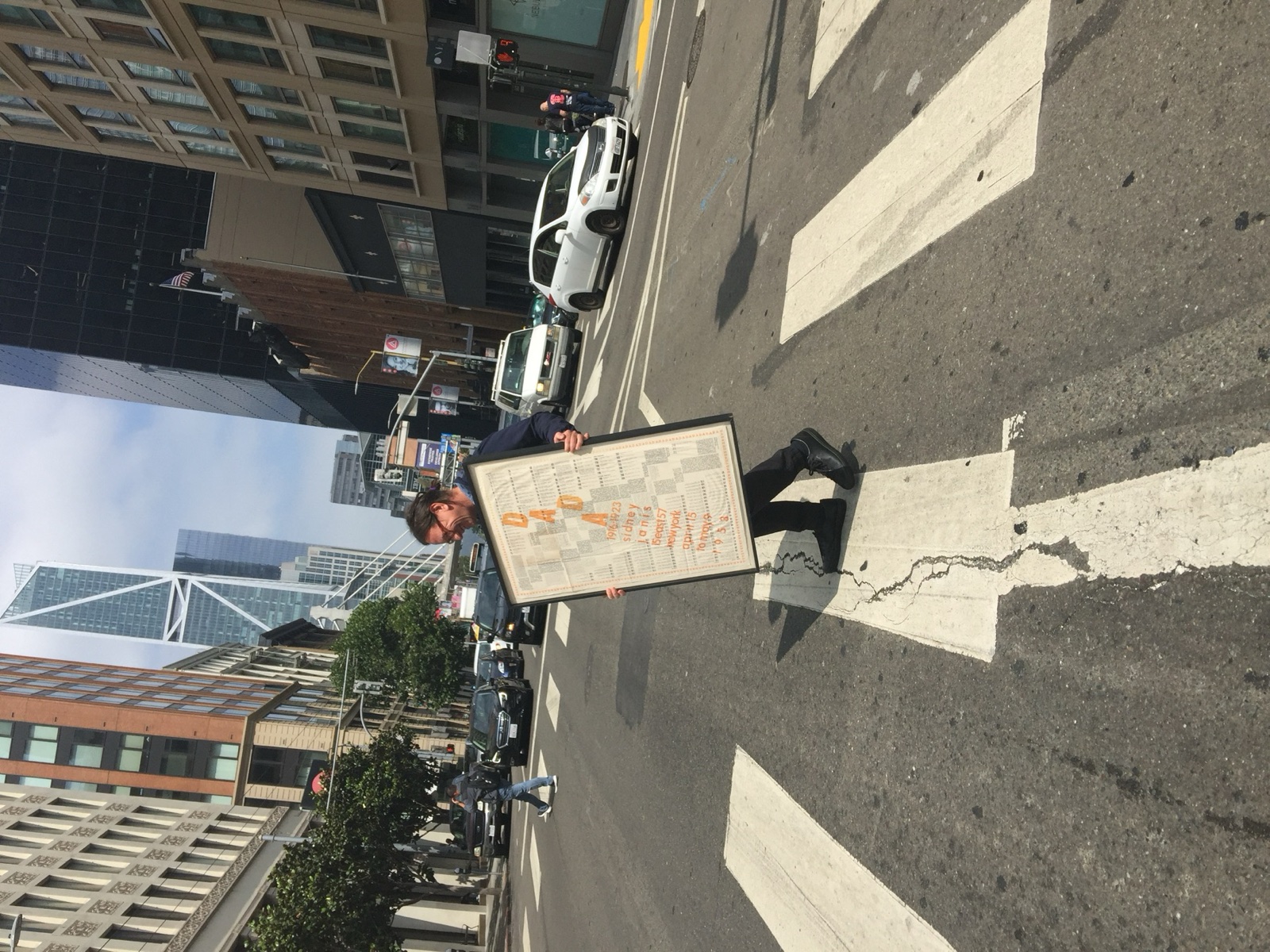 David Senior walking across the street with a poster.