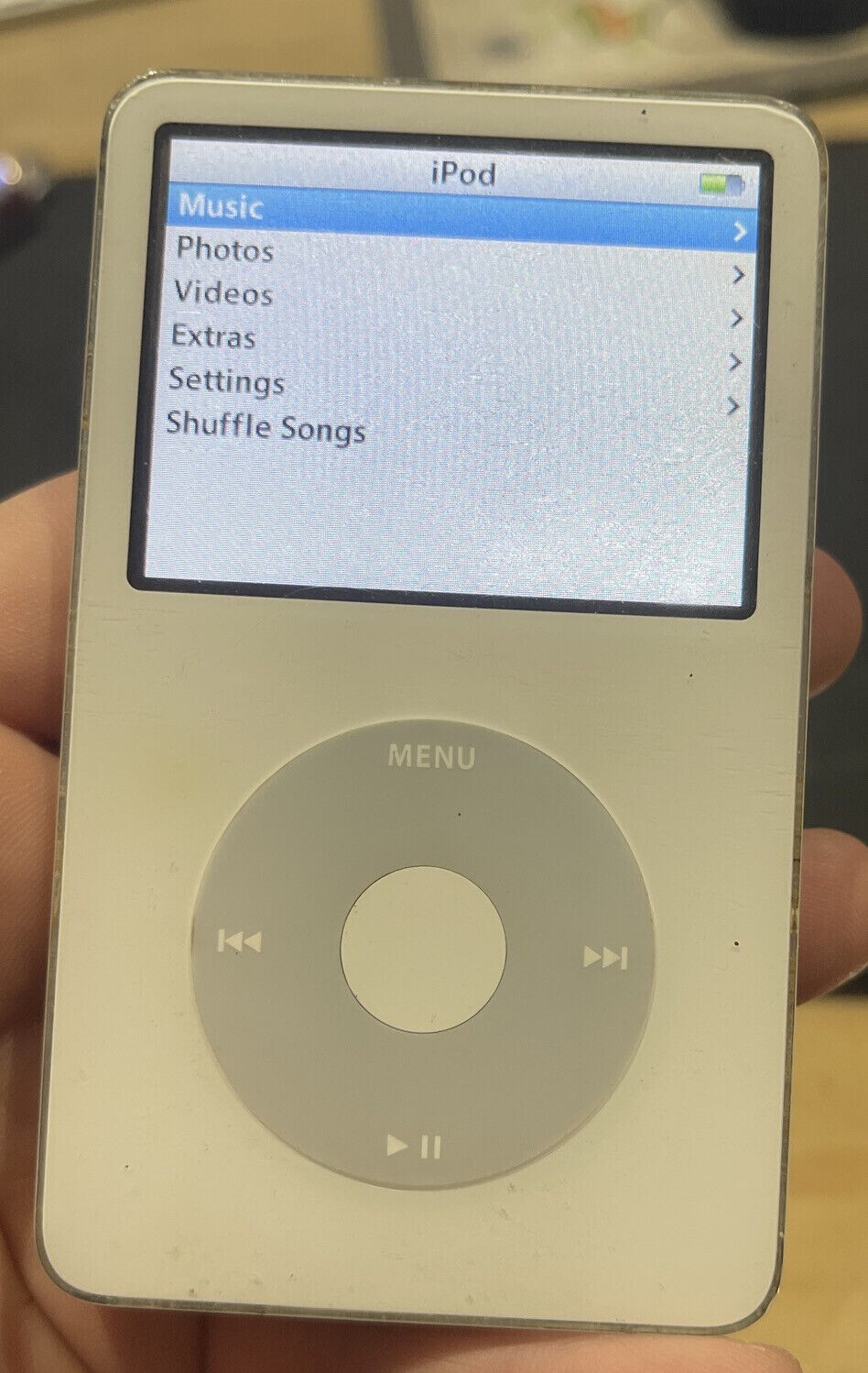 An iPod Classic with the main menu open — Music, Photos, Videos, Extras, Settings, Shuffle Songs.