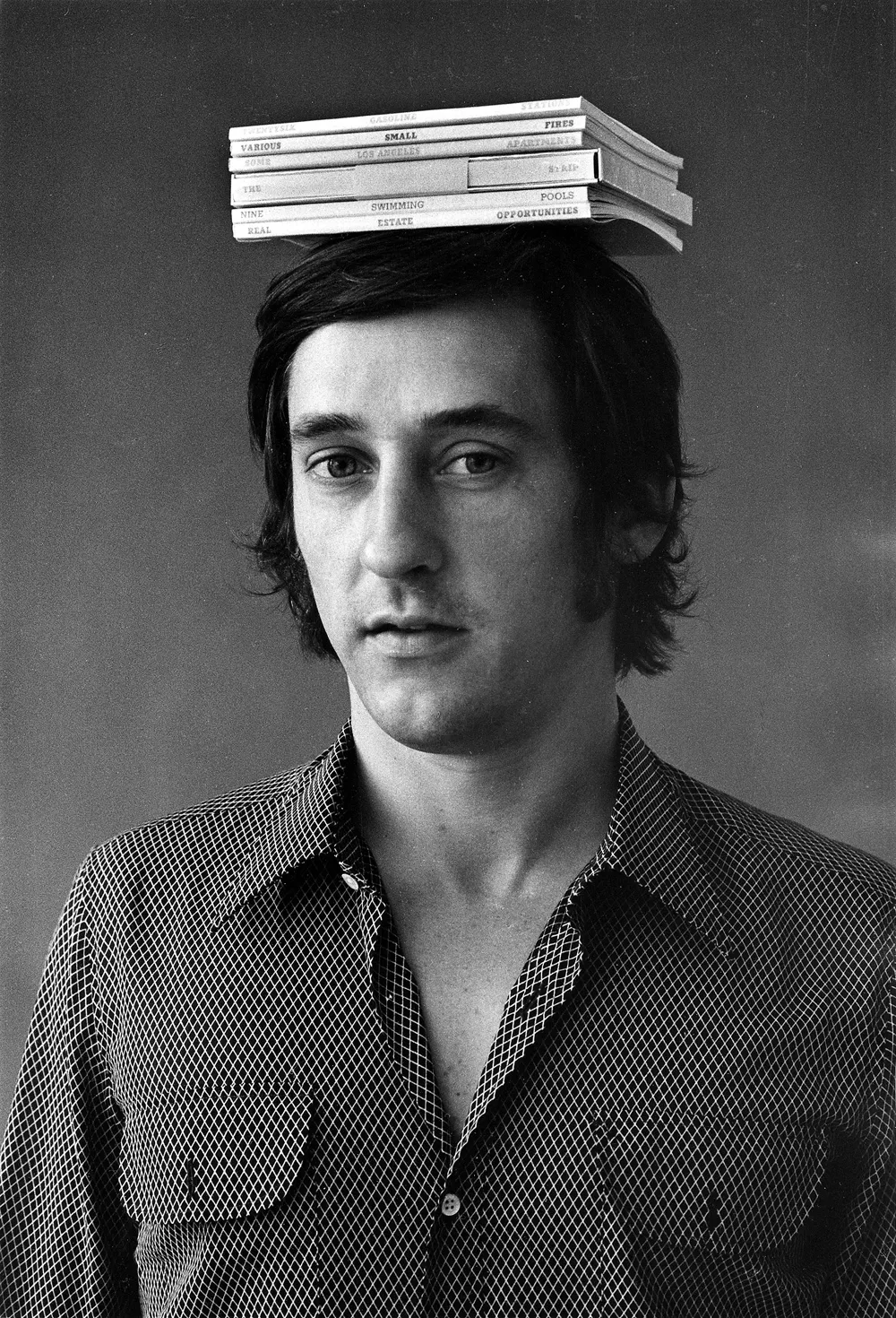 Ed Ruscha with six books, 1970. Photo by Jerry McMillan.